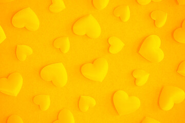 Background from hearts and sparkles. yellow hearts on a yellow background top view. Background for love flat lay. The concept of a holiday, miracles and surprises.