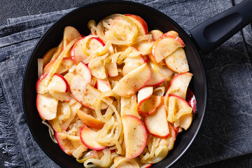 fried onion and red apple slices on skillet