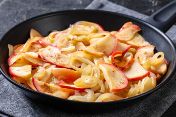 fried onion and red apple slices on skillet