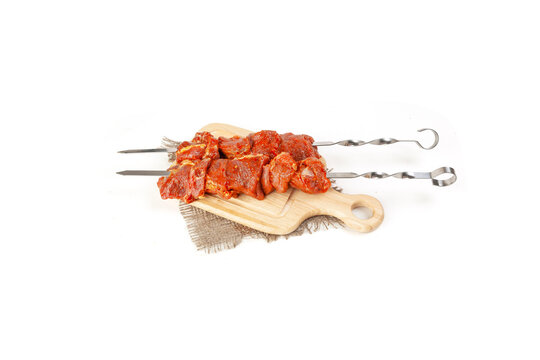 Raw meat in marinade put on skewers isolated on white background. Damp meat of beef in the marinade, Cooking shish kebab.