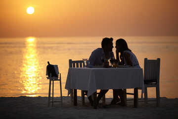 Love, ocean sunset and couple at table for romantic valentines day date at the beach in Bali in...