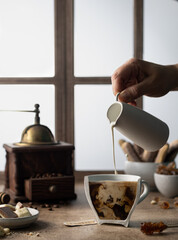 Coffee with milk in a cut cup on the background of a wooden window, with a vintage coffee grinder...