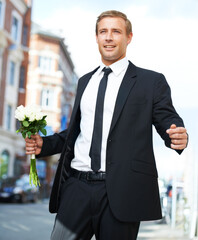 Man, gift and valentines day flowers or roses on a city street for a date, love and motivation. Model person in a formal suit with a flower bouquet to celebrate holiday or event with urban travel