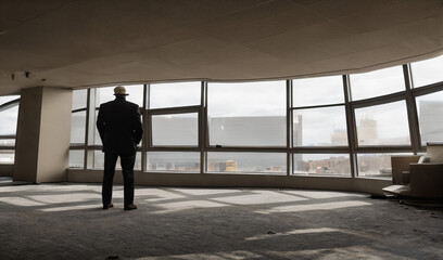 backview of an old man in an abandoned American skyscraper wih giant windows in the background - AI Generative