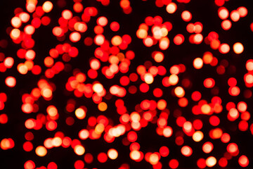 Red defocused light confetti on a black background. Bicolor bokeh background