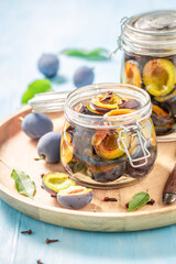 Sweet and tasty pickled plums in jar with spices.