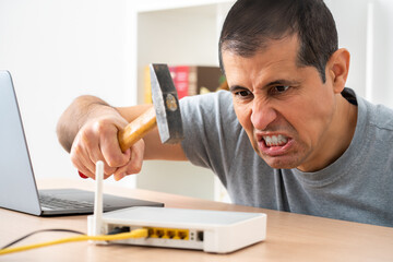 Angry man ready to destroy a computer with a hammer at home