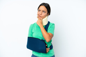 Young hispanic woman wearing a neck brace and sling isolated on white background having doubts