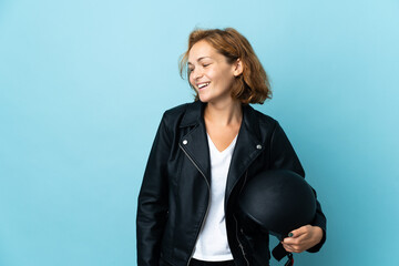 Georgian girl holding a motorcycle helmet isolated on blue background looking to the side and...