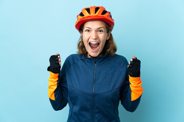 Young cyclist woman isolated on blue background celebrating a victory in winner position
