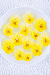 Arrangement of yellow pansy blossoms swimming in bowl