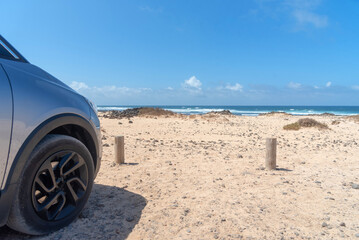 Playa El Hierro o Playa de las palomitas en la turística Fuerteventura, llena de rodolitos calvos y al fondo el tranquilo mar turquesa, por un lado la rueda de un coche