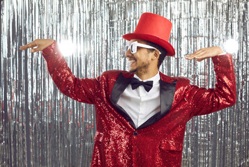 Overjoyed funny young black man in red glitter suit have fun dancing on glitter disco background....