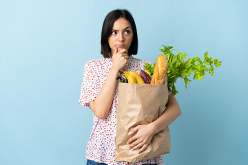 Young woman holding a grocery shopping bag having doubts
