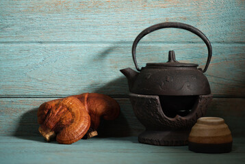 Reishi mushroom and kettle on green wood background.