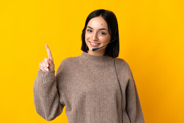 Young telemarketer woman isolated on yellow background showing and lifting a finger in sign of the...