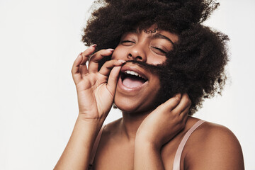 Joyful black lady making mustache with hair and smiling