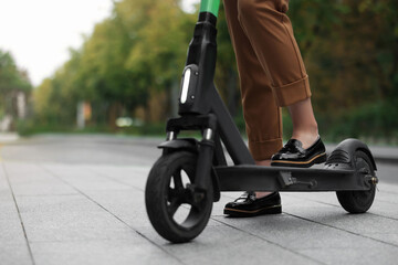 Obraz premium Businesswoman with modern electric kick scooter on city street, closeup. Space for text