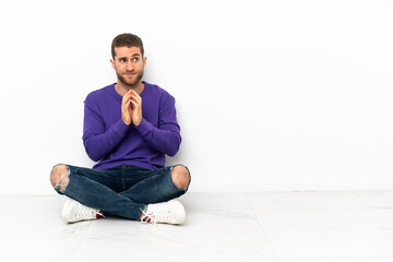 Young man sitting on the floor scheming something