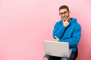Young man sitting on a chair with laptop smiling