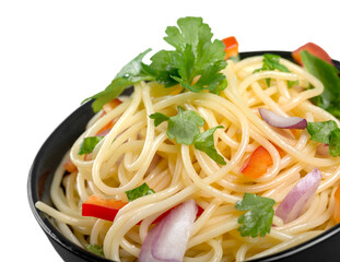 Pasta in a white bowl with tomato sauce and fresh basil set against a white napkin on a white table