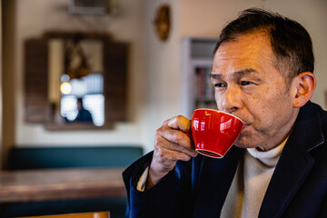 Middle-aged Asian man drinking coffee alone in the cafeteria.