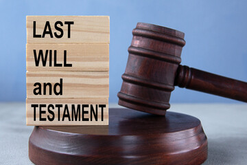 The words LAST WILL and TESTAMENT on wooden cubes against the background of the judge's gavel and stand.