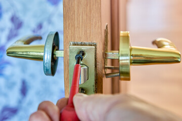 Assembling mechanism of lever door handle, locksmith tightens fixing screw using a screwdriver.