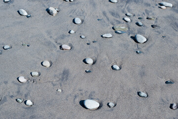 Fototapeta na wymiar Volcanic sand and stones on the ocean beach pattern texture background