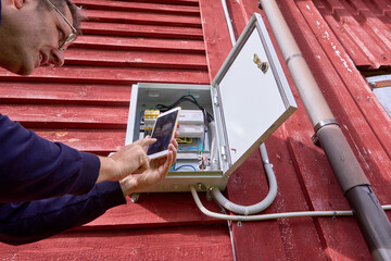 Photographing readings of an external electric meter located in electrical panel on wall of country...