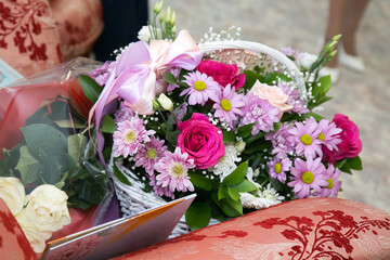A huge bouquet of roses, daisies, chrysanthemums in a white wicker basket with a bow.