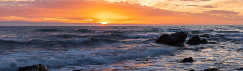Fototapeta na wymiar Waves by the ocean with dramatic sky at sunrise.
