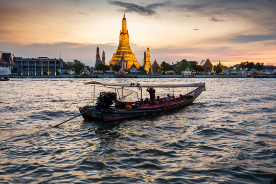 Wat Arun and boats,at sunset,along the Chao Phraya river,Bangkok,Thailand.
