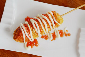 Korean corn dog or Korean hot dog is a popular street food made of sausages or mozzarella cheese on sticks and wrapped with yeasted batter and coated with breadcrumbs then deep fried to golden.
