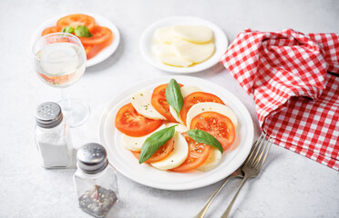 Caprese salad with tomatoes, mazzarella cheese and basil leaves in a plate
