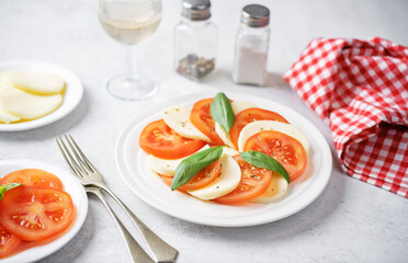 Caprese salad with tomatoes, mazzarella cheese and basil leaves in a plate