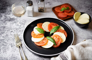 Caprese salad with tomatoes, mazzarella cheese and basil leaves in a plate