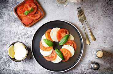 Caprese salad with tomatoes, mazzarella cheese and basil leaves in a plate