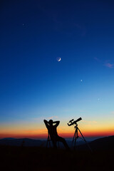 Man with astronomy telescope looking at the night sky, stars, planets, Moon and shooting stars.