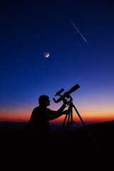 Man with astronomy telescope looking at the night sky, stars, planets, Moon and shooting stars.