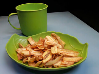 photo of banana chips on a green plate shaped like a leaf