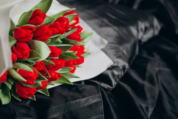 Bouquet of red tulips on black silk bed