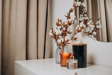 Cotton branch in vase with candle burning as decoration on table