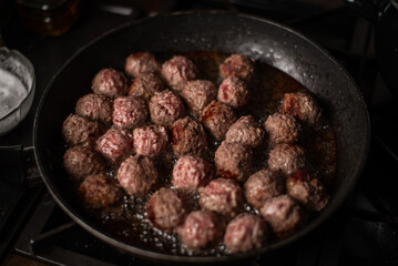 Meatballs in a frying pan. Making meatballs. Dark background.