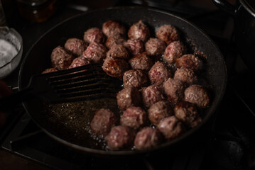 Meatballs in a frying pan. Making meatballs. Dark background.