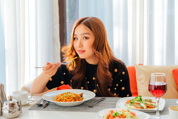 Asian woman eating dish with fried noodles