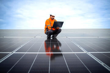 Serious solar panel worker using laptop computer and checking electricity production in sustainable...