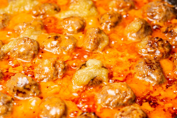 Cooking homemade meatballs in a frying pan in a sauce of tomatoes and sour cream. Close-up macro. Food background.