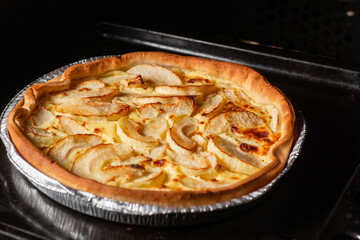 Pie with apples in the oven. Delicious round yellow veggie pie with sliced apples.