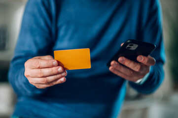 Focus on a man hand holding gold mockup credit card and a smartphone